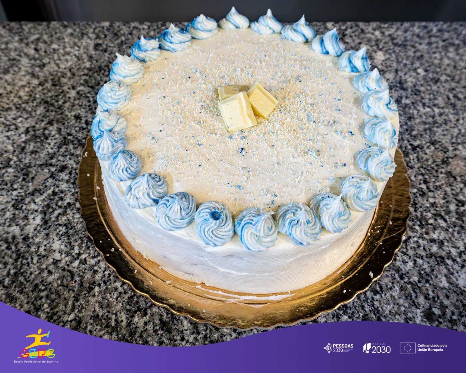 Bolo com cobertura branca e azul, coco e pedaços de chocolate branco