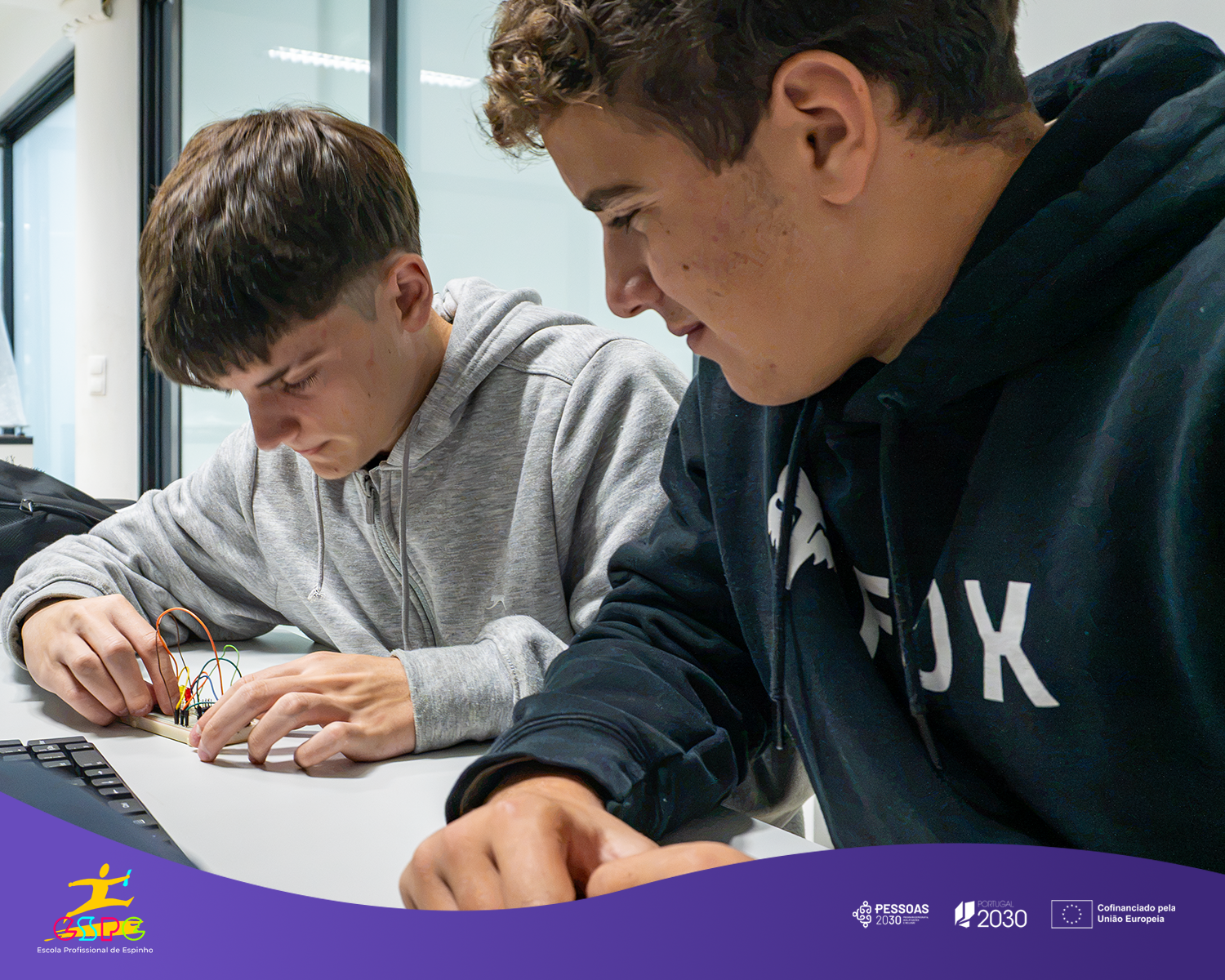 Dois alunos montam um circuito com microcontrolador numa placa de ensaio